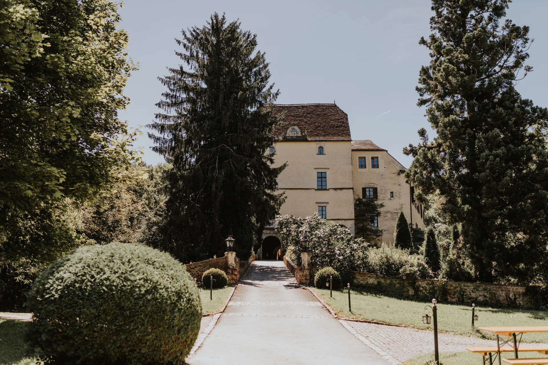Von Bäumen gesäumte Zufahrt zum Schloss Obermayerhofen an einem Sommertag